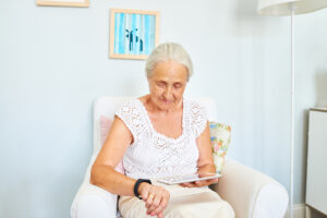 Senior woman sitting in sofa and using smart watch and digital tablet