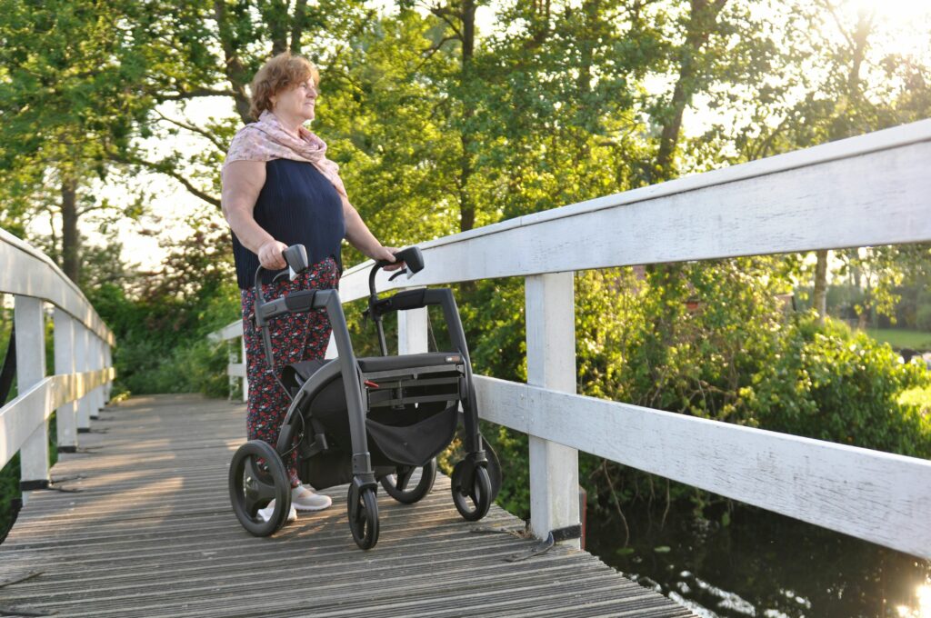 A woman using a walker standing on a bridge